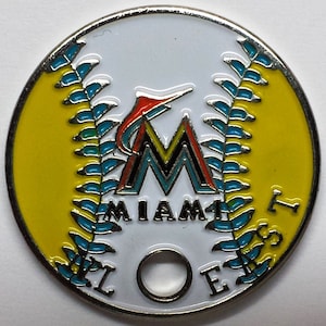 May include: A white, yellow, and blue baseball-themed metal coin with the Miami Marlins logo and the words "Miami Marlins" around the logo.
