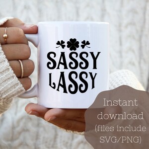 May include: White ceramic mug with the words "SASSY LASSY" in black, along with shamrock designs. The mug is held by a person. Text on the image says "Instant download (files include SVG/PNG)".