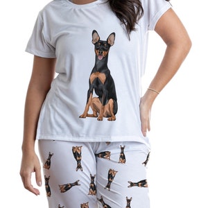 May include: White pajamas with a black and brown dog print. The top has a single dog image on the front and the pants have a repeating pattern of the dog.