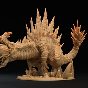 May include: A detailed miniature of a monstrous creature with a spiky back, sharp claws, and a large, round eye in its mouth. The creature is sculpted in a light brown color and appears to be made of resin.