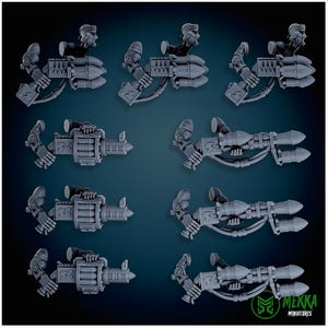 May include: A collection of gray miniature weapon models, likely for tabletop gaming or model building. The designs include missile launchers, cannons, and mechanical arms. The models are arranged on a dark blue background.