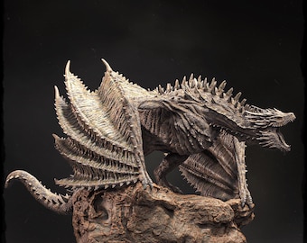May include: A detailed sculpture of a dragon with open wings, perched on a textured rock base. The dragon is primarily gray and brown, with intricate scales and sharp spines along its back. Its mouth is open, revealing teeth.