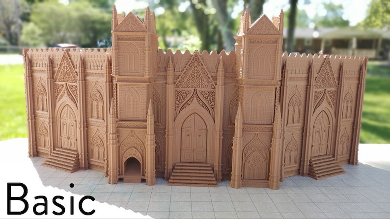 May include: A 3D printed model of a large, detailed gothic cathedral with intricate carvings and a pointed archway. The model is made of a light brown plastic and is set against a green grassy background.