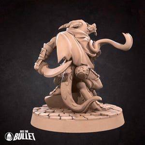 May include: A miniature figurine of a brown dragon-like creature with a long tail and a cloak. The creature is holding a dagger and has a yellow eye. The figurine is standing on a circular base with a cobblestone design.