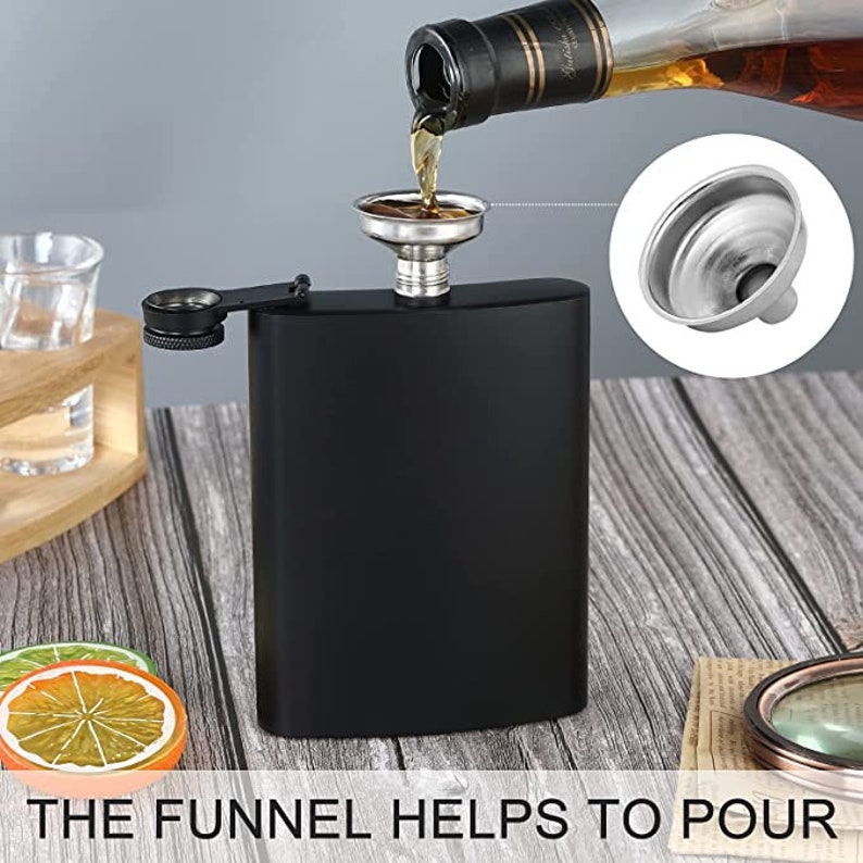 May include: A black stainless steel hip flask with a silver funnel. The funnel is being used to pour liquid into the flask. The flask has a screw-on cap with a small silver loop.