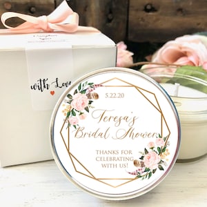 Pode incluir: Uma vela branca com um r&oacute;tulo de design floral. O r&oacute;tulo tem formas geom&eacute;tricas douradas e o texto "5.22.20 Teresa's Bridal Shower Thanks for celebrating with us!"