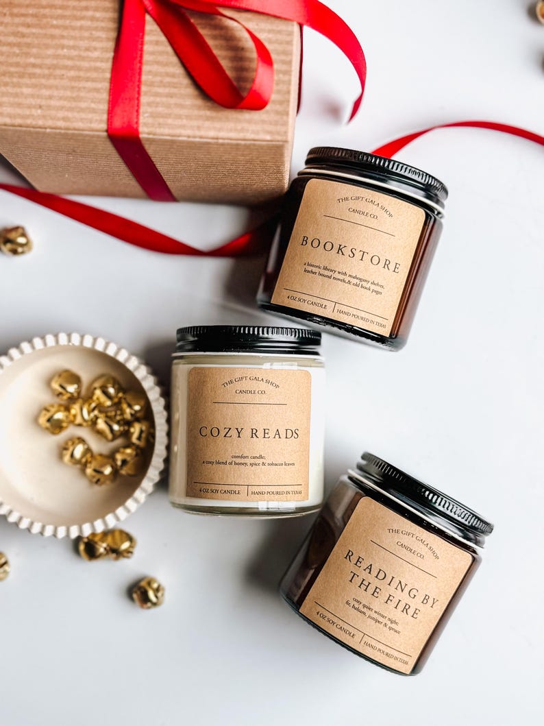 May include: Three soy candles in glass jars with black lids. The candles are labeled "Bookstore", "Cozy Reads", and "Reading by the Fire". Each candle has a brown label with white text and is hand-poured in Texas.