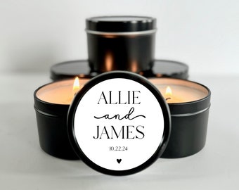 May include: Two black candle jars with white labels. The label says "Allie and James" with the date "10.22.24" and a small heart.
