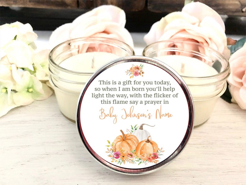Może przedstawiać: Mały słoik ze świeczką z białą świecą i etykietą z napisem "This is a gift for you today, so when I am born you'll help light the way, with the flicker of this flame say a prayer in Baby Johnson's Name". Etykieta ma kwiatowy wz&oacute;r z dyniami.