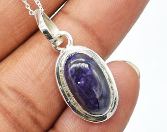 May include: A silver pendant necklace with a purple oval gemstone. The pendant has a detailed silver border.