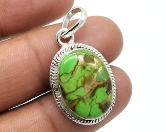 Puede incluir: Un colgante ovalado con una piedra de color verde lima vibrante con vetas de matriz marrón, engastado en un marco de plata pulida con un borde de cuerda trenzada y una sencilla anilla de plata en la parte superior.