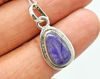 May include: A silver pendant necklace with a purple and white gemstone. The pendant is oval shaped and has a silver border.
