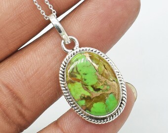 Puede incluir: Un colgante de plata con una piedra ovalada de turquesa verde y marrón engastada en un bisel de plata. El colgante está en una cadena de plata.