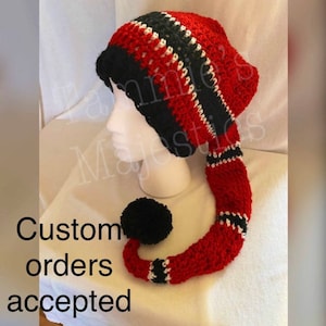 Puede incluir: Sombrero de punto rojo, negro y blanco con una cola larga. El sombrero tiene un pompón en el extremo de la cola. Se aceptan pedidos personalizados.