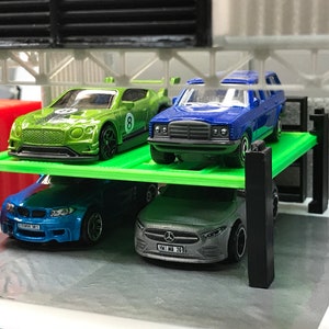 Peut inclure: Un garage de stationnement pour voitures miniatures vert, bleu et argent avec quatre voitures miniatures gar&eacute;es &agrave; l'int&eacute;rieur. Les voitures sont une Bentley verte, une Mercedes-Benz bleue, une BMW bleue et une Mercedes-Benz argent&eacute;e.