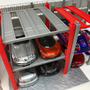 Peut inclure: Un garage &agrave; voitures miniature &agrave; plusieurs niveaux avec des supports en m&eacute;tal gris et rouge. Le garage est rempli de voitures miniatures de diff&eacute;rentes couleurs, notamment argent, rouge, bleu et blanc.