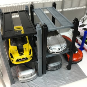 Peut inclure: Un garage &agrave; voitures miniature &agrave; plusieurs niveaux avec quatre voitures miniatures. Le garage est en plastique noir et gris. Les voitures sont jaunes, argent&eacute;es, blanches et orange.
