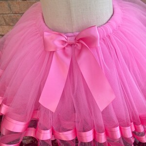 May include: Pink tulle tutu skirt with a pink satin bow and pink satin ribbon trim.