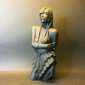 May include: Black and white bust sculpture of a woman with long hair, wearing a skirt and a belt. The sculpture is made of a smooth, matt material.