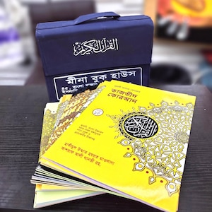 May include: A yellow book with the title "Tajveed Quran" in Bengali script. The book is part of a set of books in a blue carrying case. The case has the Arabic word for "Quran" on it.