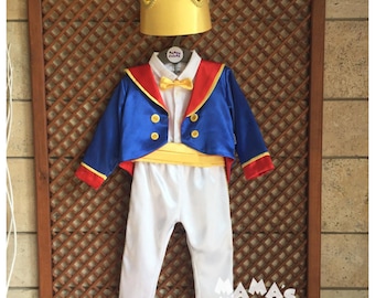 May include: A blue and red prince costume for a child, featuring a jacket, trousers, and a gold crown. The jacket has gold buttons and a yellow sash. The trousers are white. The crown has gold accents.