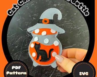 May include: A felt Halloween decoration in the shape of a cauldron potion bottle. The bottle is gray with white polka dots and an orange potion. A black cat silhouette is inside the potion. The text "Cat Cauldron Potion Bottle" is arched above the bottle.