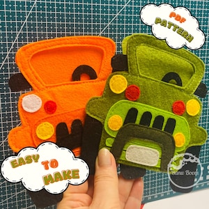 Può includere: Due camioncini giocattolo in feltro, uno arancione e uno verde, con il testo "PDF PATTERN" e "EASY TO MAKE" in una forma di nuvola.