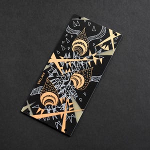 May include: A rectangular black panel featuring a graphic design with peach-coloured teardrop shapes, white geometric line patterns, and triangles. The text ISN'TSZS is printed in white on the left side. The panel has four small circular mounting holes.
