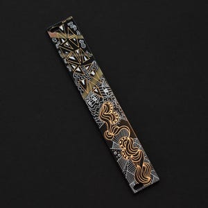 May include: A black and gold metal bookmark with a geometric and abstract design. The bookmark features a white and gold pattern with a black background.