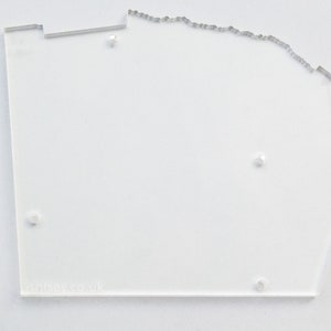 Può includere: Un modello in acrilico trasparente con un bordo irregolare e diversi piccoli fori. Il modello ha il testo "ISENSE.CO.UK" stampato sul fondo.