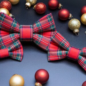 May include: Two red and green plaid bow ties with a festive Christmas ornament theme. The ornaments are red, gold, and white.