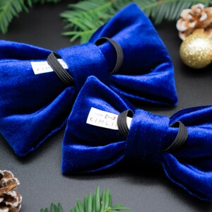 May include: Two blue velvet bow ties with black elastic bands. The bow ties have a white label with the text "KIMLIN" on them.