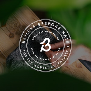 May include: A white circle logo with the text "Bailey's Bespoke Hats" and "For the Modest Adventurer" around the edge. The logo also includes the text "Hand-Crafted in the UK", "100% Recyclable Packaging" and a stylized letter "B".