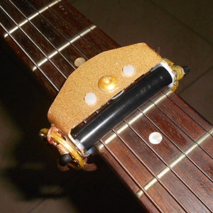 Rolling capo for electric guitar. Glistening gold lacquer finish. Handmade in Spain.