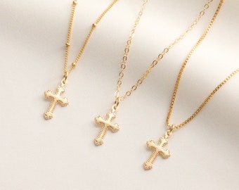 May include: Three gold necklaces with delicate cross pendants. Each necklace features a different chain style.