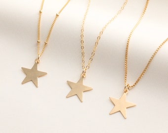 May include: Three gold necklaces with star pendants. Each necklace has a different chain style. The necklaces are on a white background.