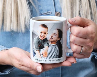 Könnte beinhalten: Eine weiße Keramiktasse mit einem Foto eines Kindes und eines Erwachsenen, die lächeln. Die Tasse hat den Text "From your little monster" unten aufgedruckt.