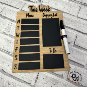 May include: A wooden weekly planner with a chalkboard surface. The planner has sections for "This Week", "Menu", "Shopping List", and "To Do". It comes with a white dry-erase marker.