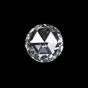 Op de afbeelding: Een heldere, rond geslepen diamant met meerdere facetten, die het licht reflecteert. De edelsteen is geplaatst tegen een zwarte achtergrond, wat de schittering en helderheid benadrukt. De vorm van de diamant is een perfecte cirkel.