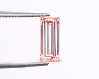 May include: A rectangular, light pink gemstone held by tweezers. The gem has a vertical, striped pattern and a polished, faceted surface. The gem is a soft, pastel color, and the tweezers are silver.