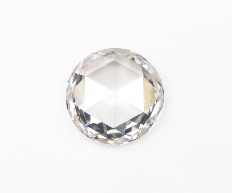 May include: A clear, round-cut gemstone with multiple facets, reflecting light. The gem is set against a white background, highlighting its clarity and brilliance. This gemstone is suitable for jewelry making.