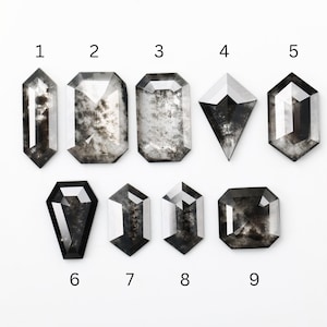 Puede incluir: Nueve piedras preciosas grises facetadas de diferentes formas se muestran sobre un fondo blanco. La colección incluye cortes rectangulares, de cometa y esmeralda, cada uno con patrones internos únicos y superficies reflectantes. Las piedras están numeradas del 1 al 9.