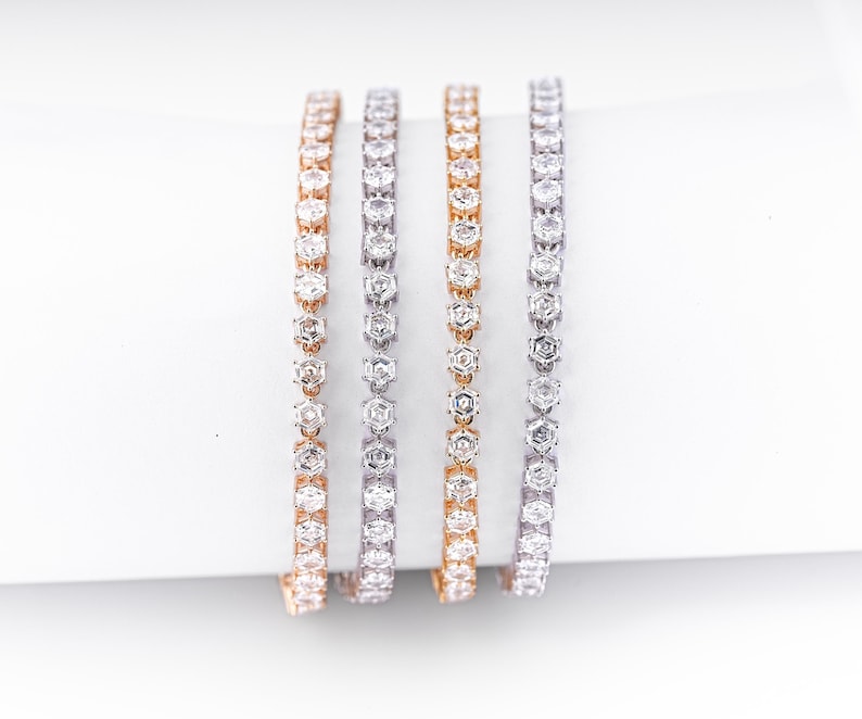 K&ouml;nnte beinhalten: Vier zarte Armb&auml;nder, jedes mit einer Reihe funkelnder, klarer Edelsteine. Die Armb&auml;nder sind in Ros&eacute;gold-, Silber- und Goldt&ouml;nen gehalten und schaffen eine luxuri&ouml;se und elegante &Auml;sthetik. Die Edelsteine sind eng aneinander gesetzt.
