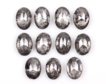 Pode incluir: Dez diamantes pretos de forma oval com corte facetado. Os diamantes estão dispostos em três filas sobre um fundo branco.