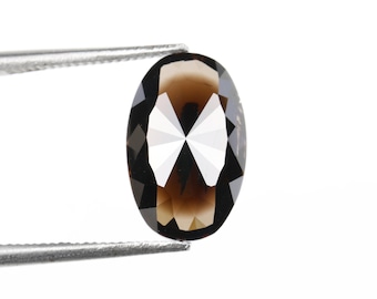 May include: An oval-cut, faceted smoky quartz gemstone held by a pair of silver tweezers. The gemstone has a dark brown color with a brilliant, reflective surface, showcasing multiple facets.