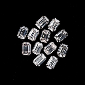 Puede incluir: Un grupo de 12 diamantes de talla esmeralda transparentes sobre un fondo negro.