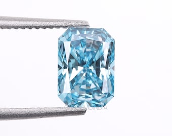 May include: A light blue, rectangular, faceted gemstone with a square shape. The gemstone is held by a pair of tweezers.