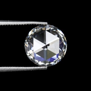 May include: A clear, round-cut diamond held by silver tweezers against a black background. The diamond's facets reflect light, creating a brilliant display of white and blue hues. The gem is a focal point, showcasing its clarity and cut.