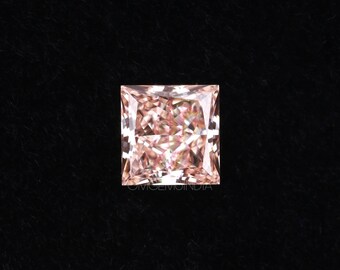 May include: A square-shaped, light pink diamond with a faceted cut. The diamond is set against a black background.