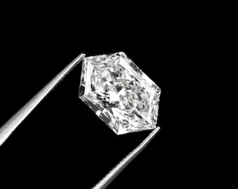 May include: A radiant-cut diamond held by silver tweezers against a black background. The diamond's facets reflect light, showcasing its brilliance. The shape is a modified octagon, with a flat top and a pointed bottom. The diamond is a clear, colorless gemstone.